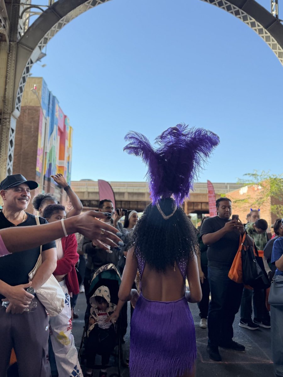 A dancer in purple feathers leading the crowd under the arch
