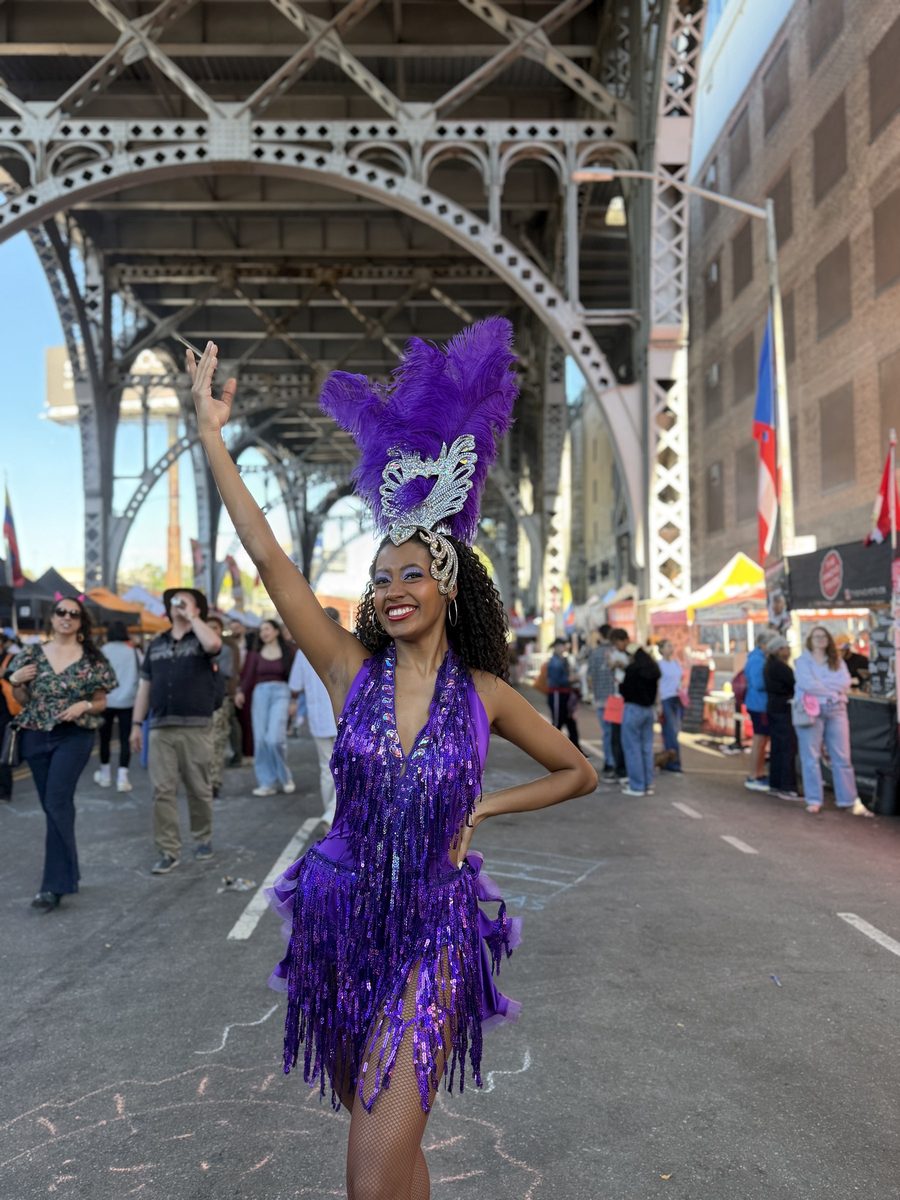 A samba dancer in purple feathers in the middle of the block under the viaduct