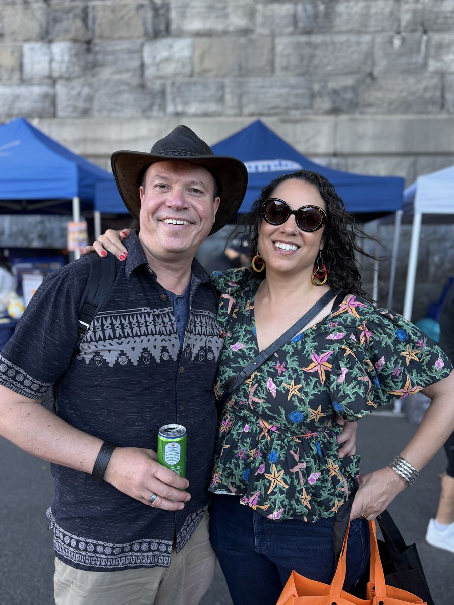 A couple smiling on the block, drink in hand